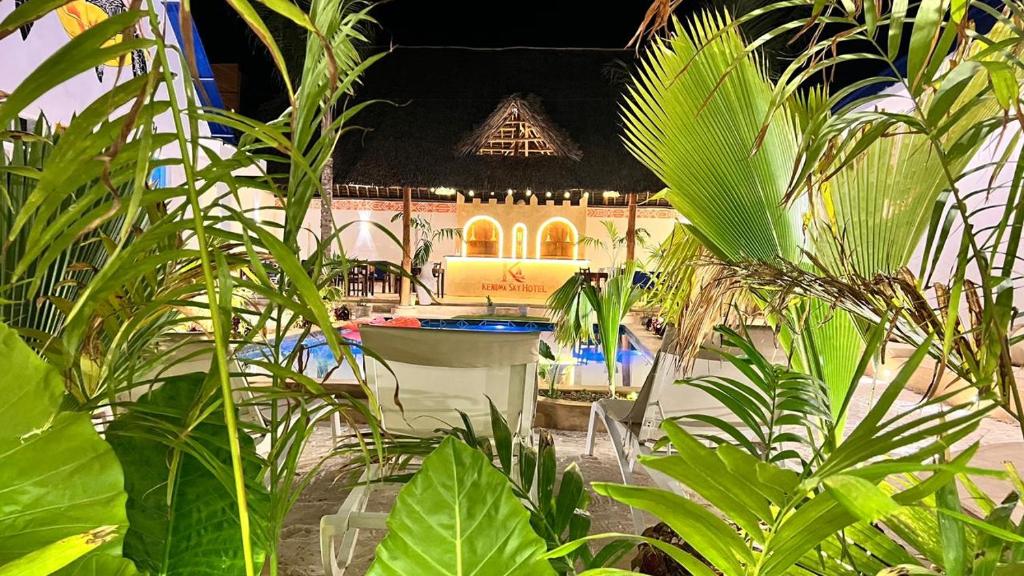 Palm fronds framing the lit thatched bar across the pool