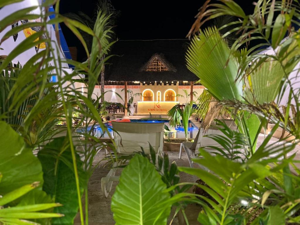 The thatched roof of the bar seen across the pool through palms
