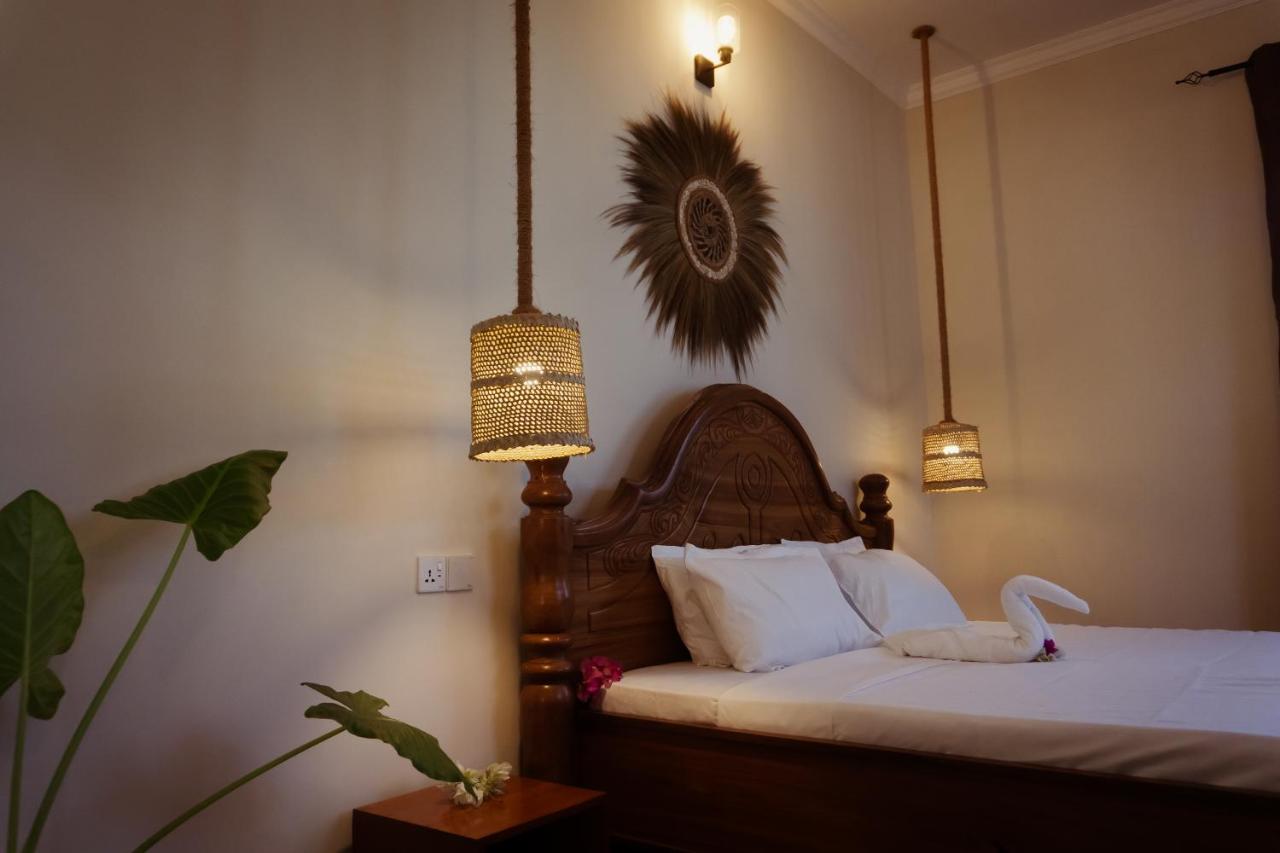 A made bed beneath a woven wall disc and bedside lamps