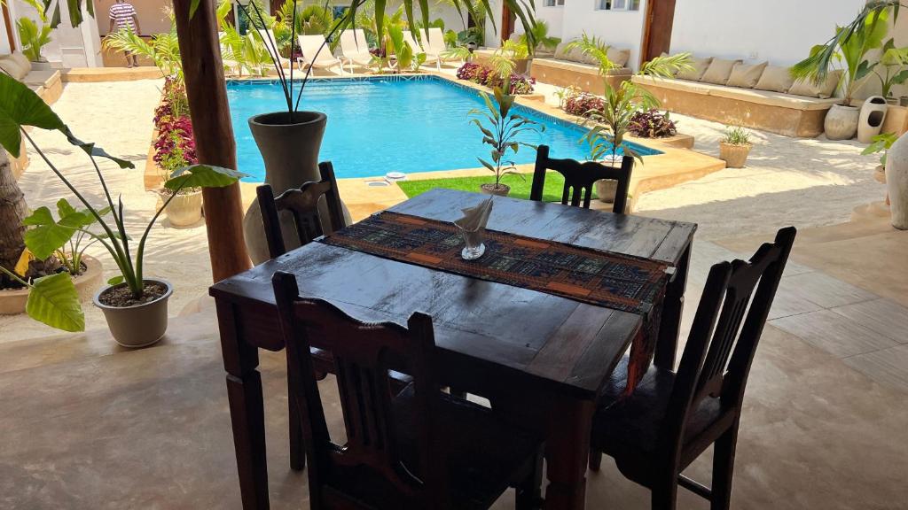A wooden dining table on the terrace with the pool behind